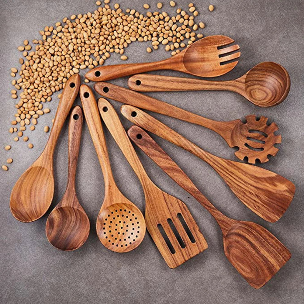 Set of wooden kitchen utensils on a gray surface with scattered lentils.
