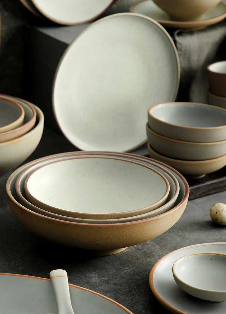 Set of ceramic bowls and plates on a dark surface