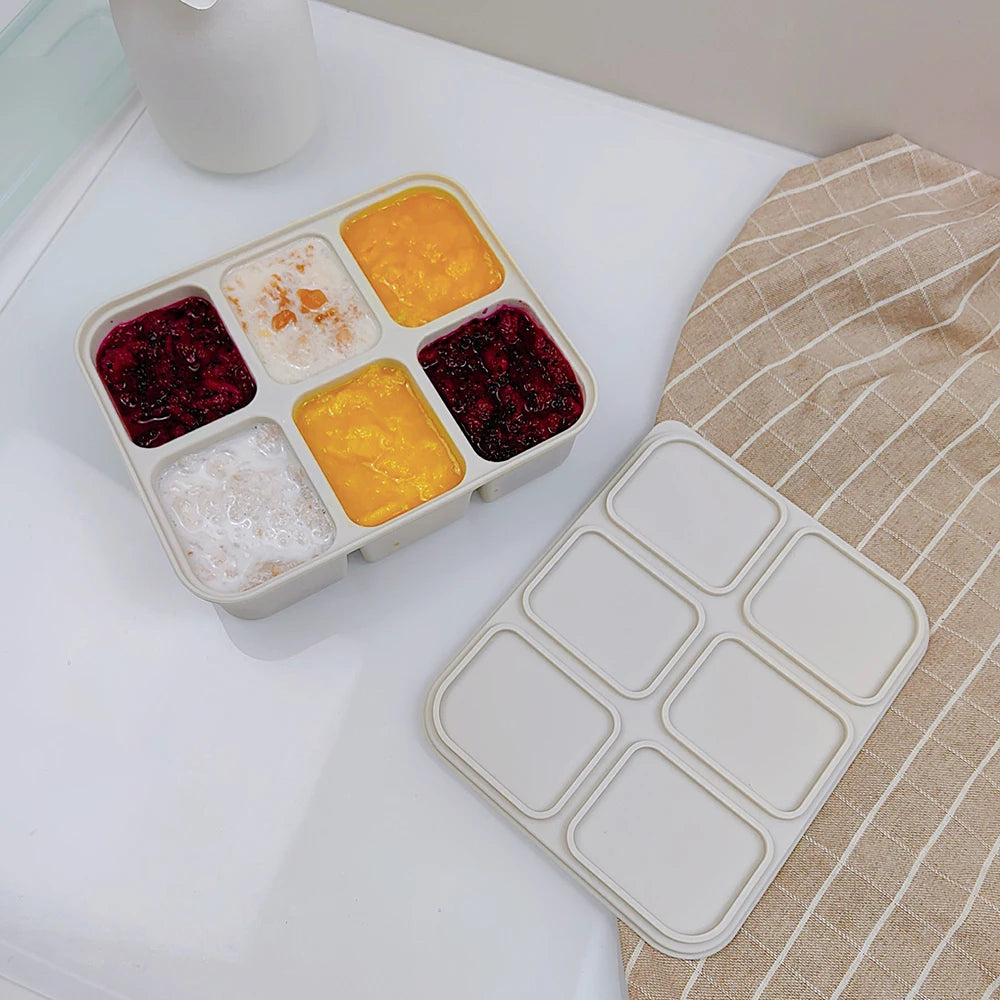 Rectangular food ice tray with compartments filled with different types of food on a white surface.