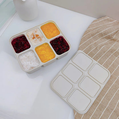 Rectangular food ice tray with compartments filled with different types of food on a white surface.