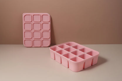 Pink silicone ice cube tray with dimensions on a beige background